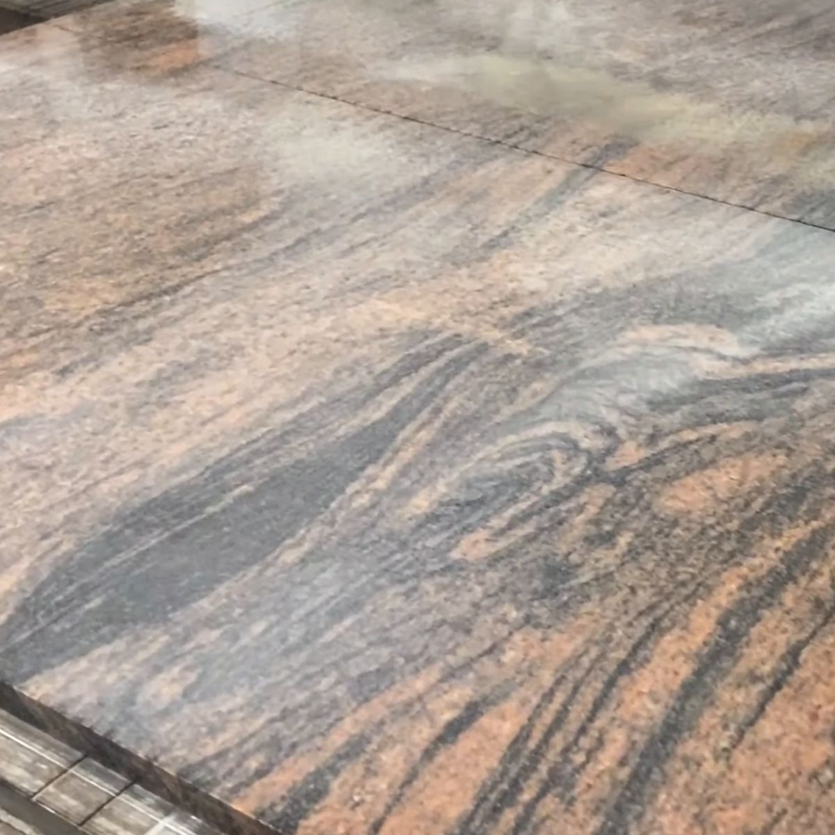 Granit Multicolor Red z bliska: rdzawoczerwone i szare, płynące pasy